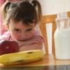 toddler girl scowls over fruit and milk