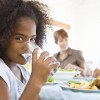 girl drinking water with a healthy meal