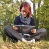 young woman uses tablet in forest