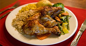 A complete chicken dinner with rice, corn, bread, and steamed vegetables.