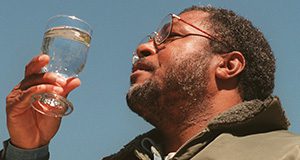 A man examines a glass of water in the sunlight.
