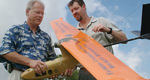 Franklin Percival, left, and Peter Ifju, professors at the University of Florida, examine a small plane that can photograph and monitor wildlife and their habitats - Oct. 19, 2004. Controlled by its own on-board computer, the plane stores and downlinks high-quality video and flight data to researchers on the ground. The unmanned aerial vehicle, or UAV, is being developed by UF's College of Engineering in cooperation with UF's Institute of Food and Agricultural Sciences. (AP photo/University of Florida/IFAS/Marisol Amador)