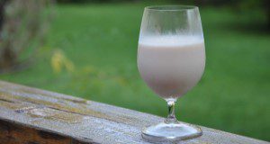 A glass goblet of soy milk resting on a wet wooden balcony outside. Credit: Lincoln Zotarelli, UF/IFAS